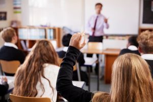 Female student raising hand to ask a question in a classroom